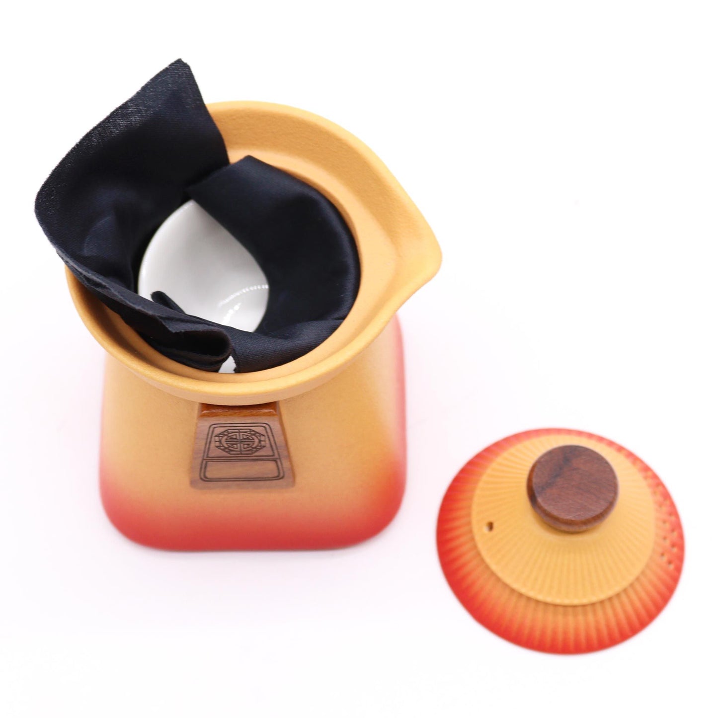 Orange earth ceramic teapot with a black cloth and a separate lid.