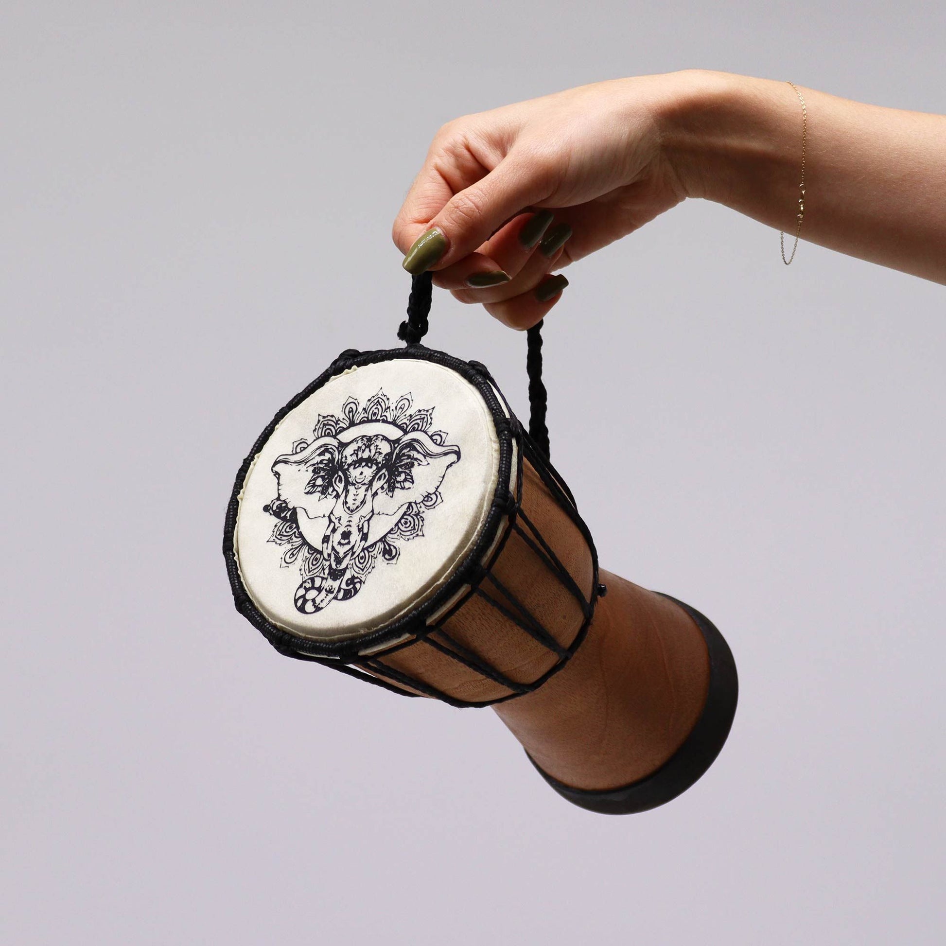 Handmade djembe drum with elephant motif held by a hand.