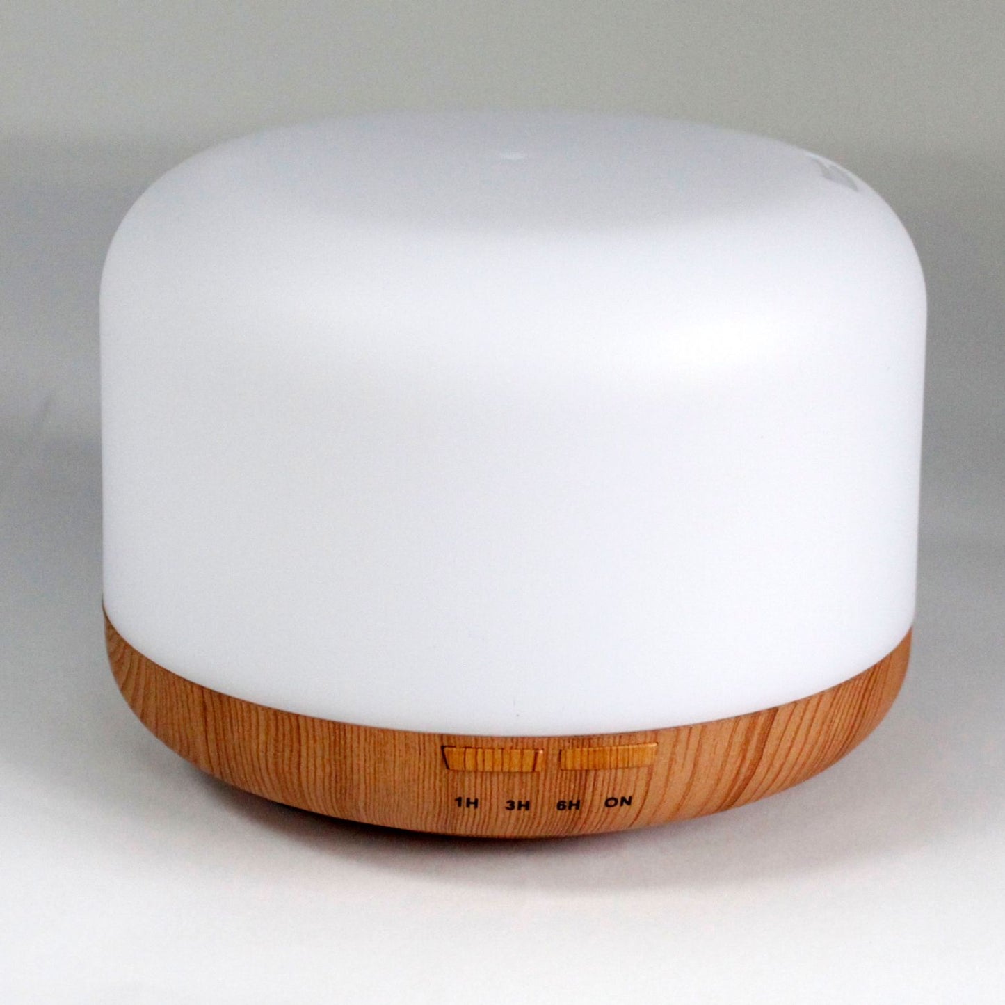 A white pod-shaped aroma diffuser with a wood-grain base and timer buttons.