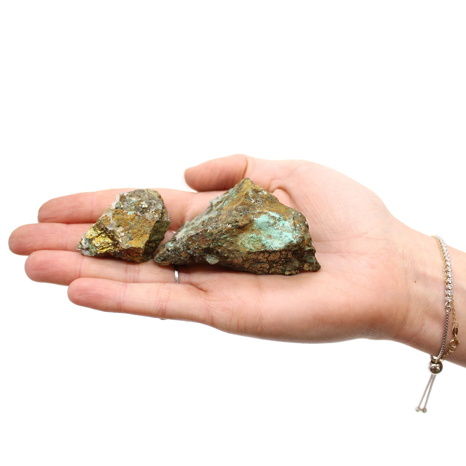Hand hält zwei rohe Chalkopyrit-Steine mit goldenem und grünem Glanz.