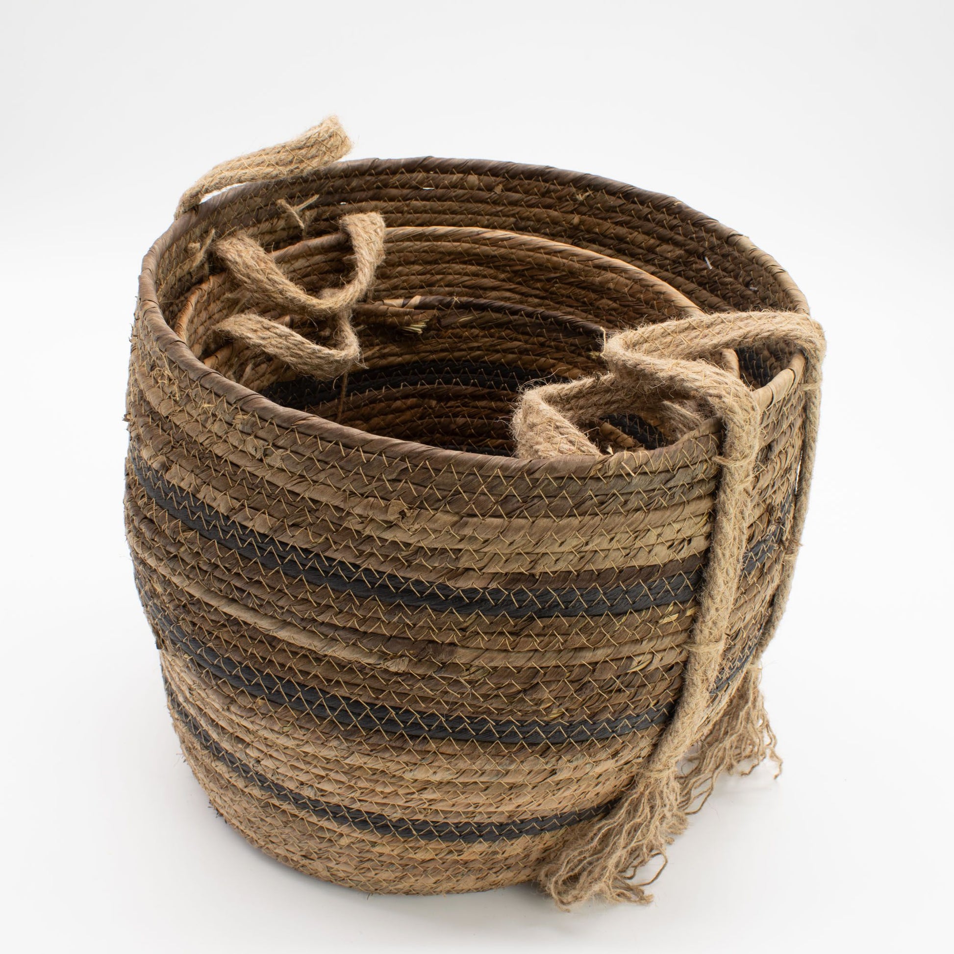 A set of three woven banana leaf and seagrass baskets in natural brown tones with rope handles.
