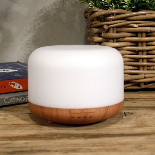 A white and wood-grain aroma diffuser with a woven basket and books in the background.