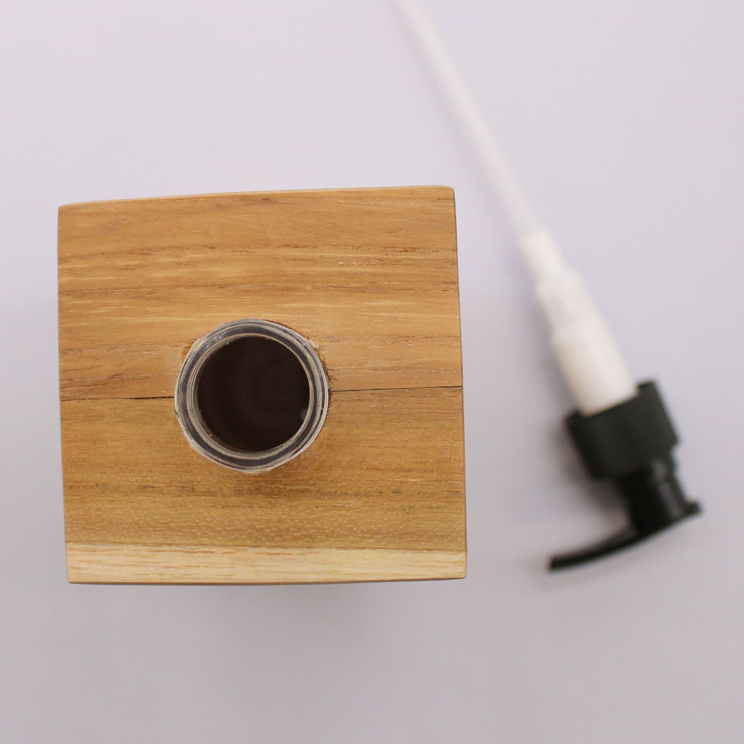 Natural teakwood square soap dispenser with a pump.