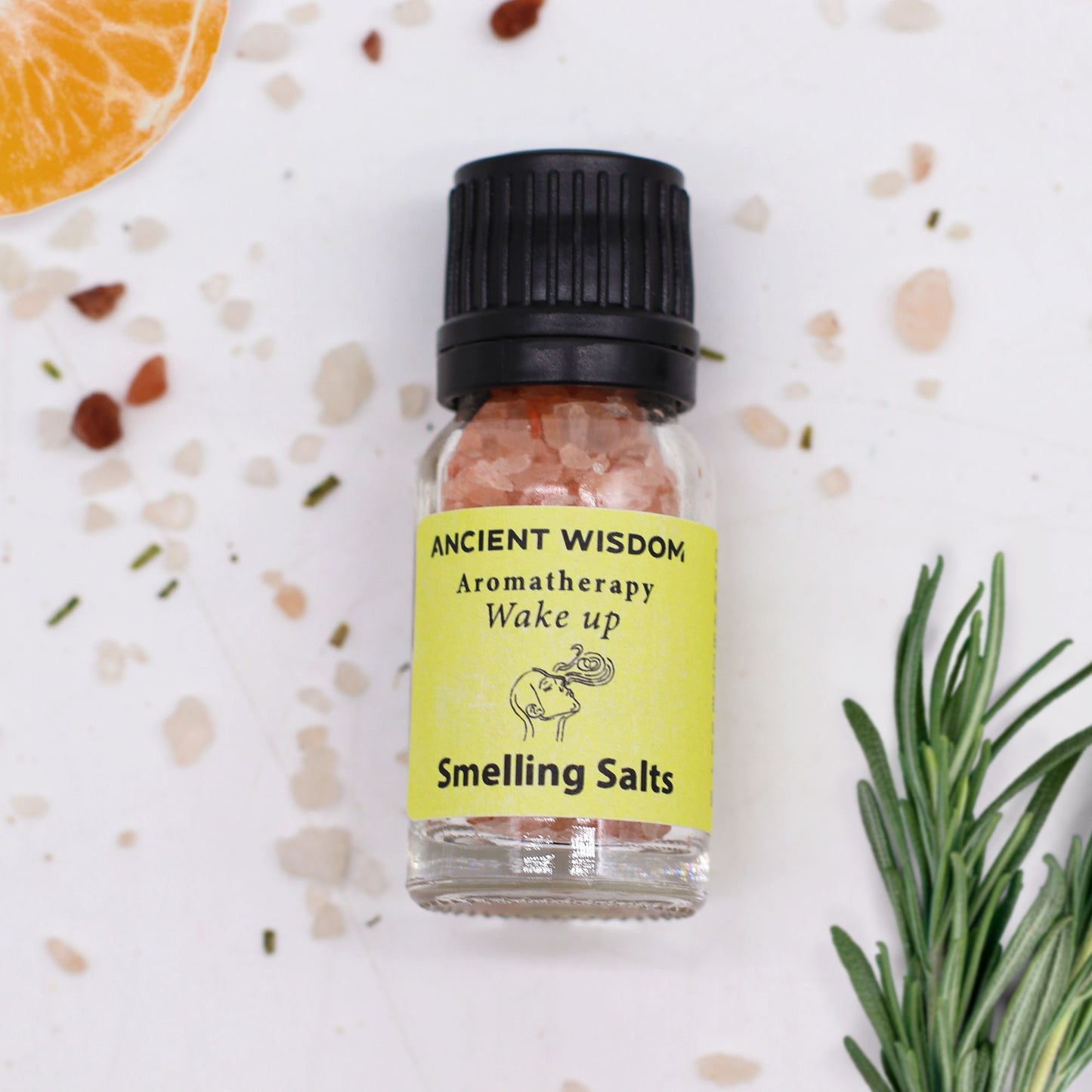 A small glass bottle of pink smelling salts with a yellow label that reads "Ancient Wisdom Aromatherapy Wake Up Smelling Salts".