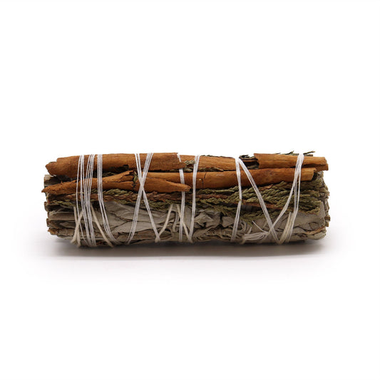 Smudge stick bundle of white sage, cedar, and cinnamon sticks tied with white string.