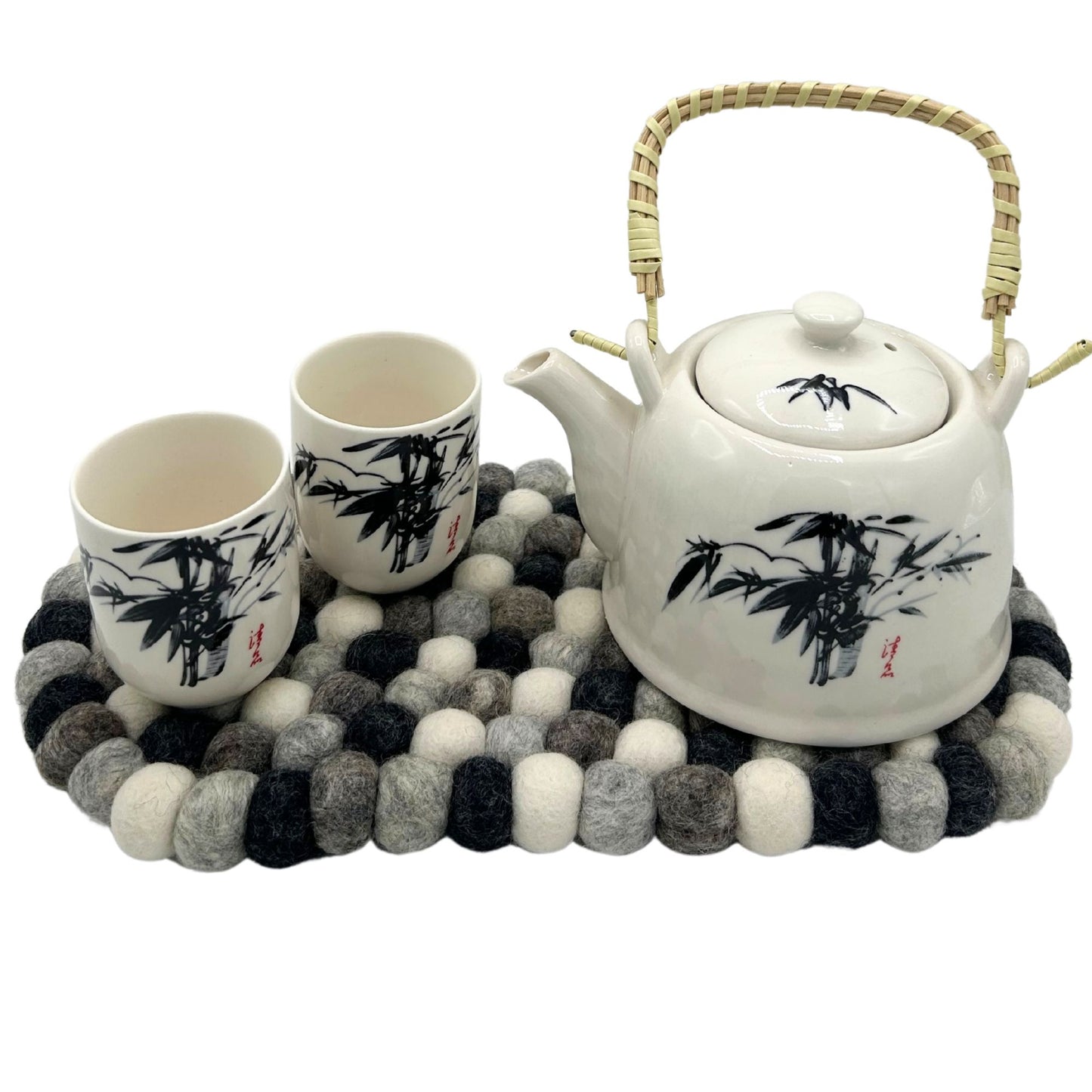 Oval felt ball mat in multi-grey colors with a white teapot and two cups.