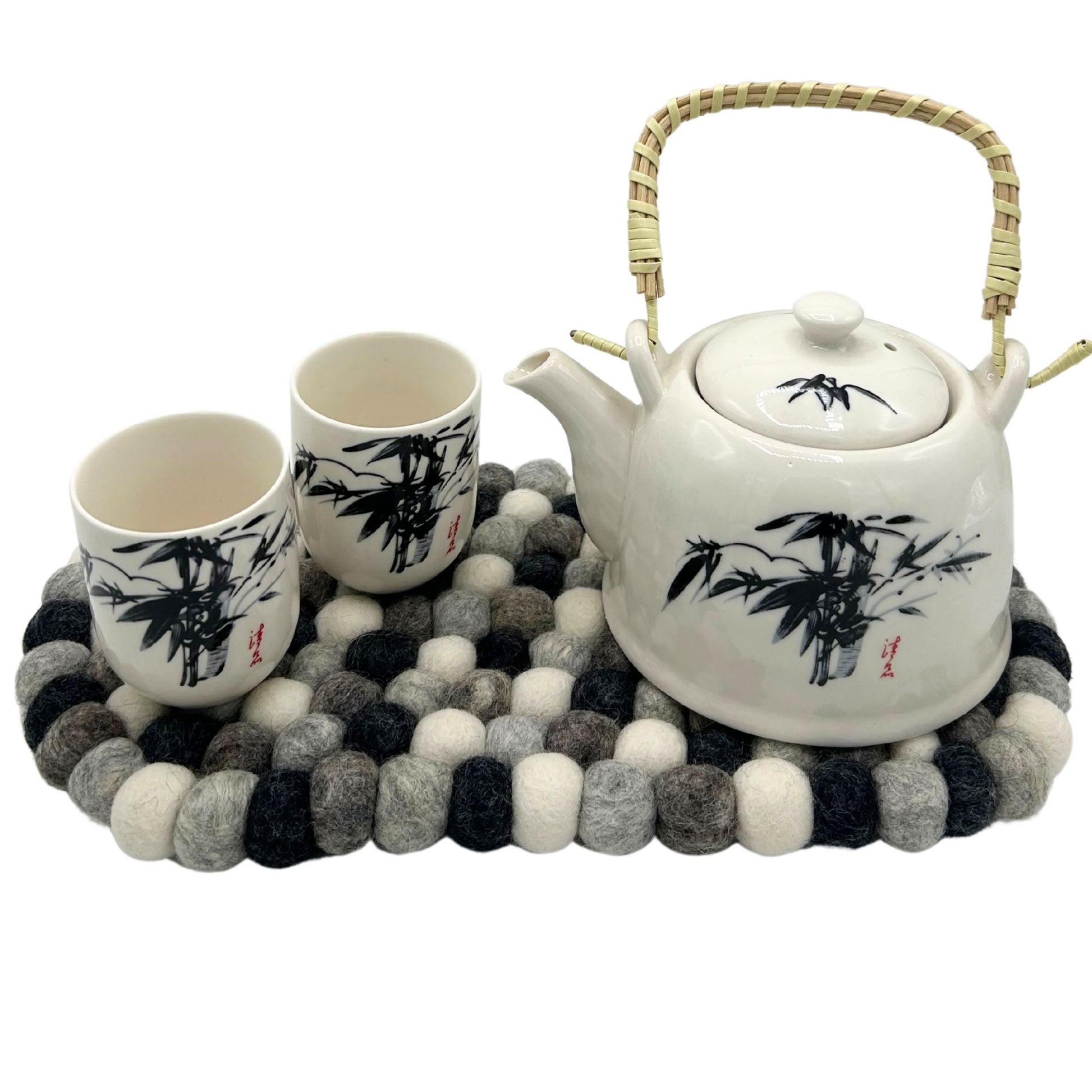 Oval felt ball mat in multi-grey colors with a white teapot and two cups.