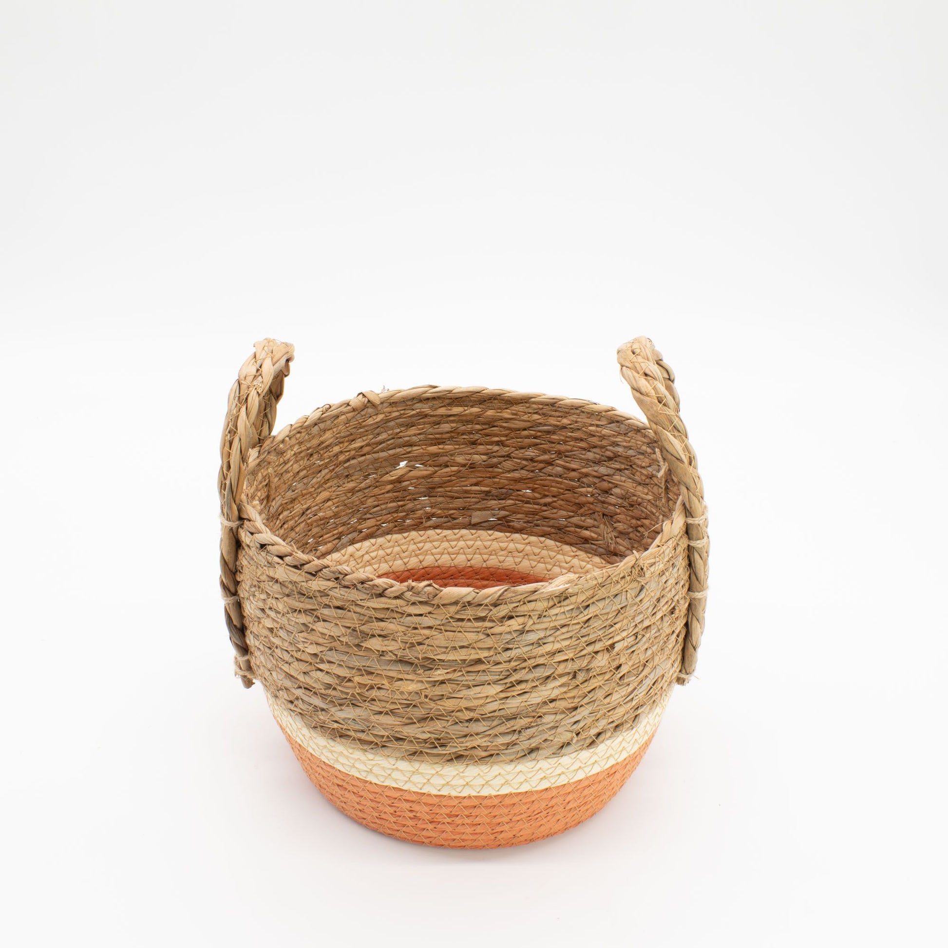 A round straw and seagrass basket with handles, featuring natural and orange bands.