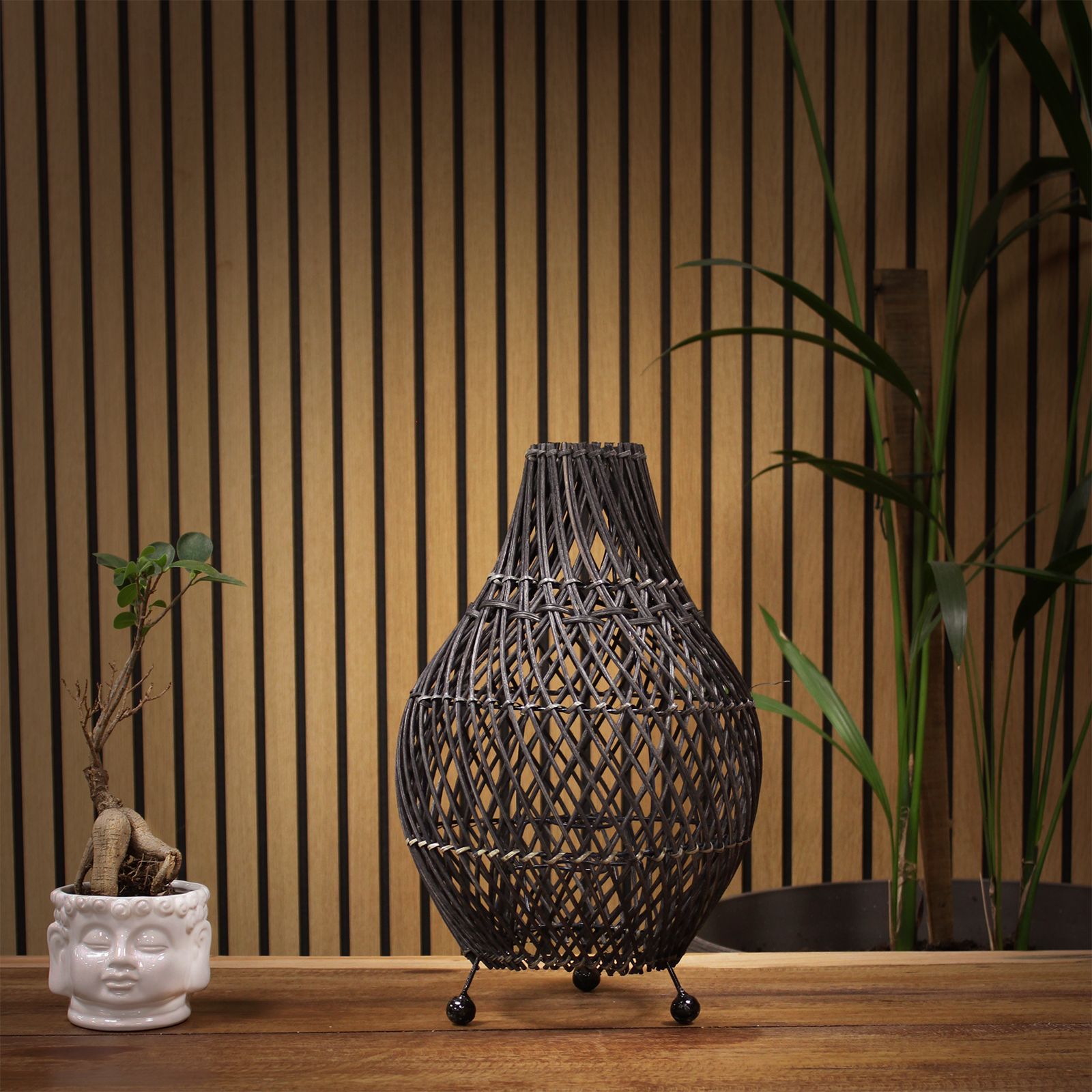 Handgefertigte Rattan-Tischlampe mit offenem Geflecht und drei Kugelfüßen.