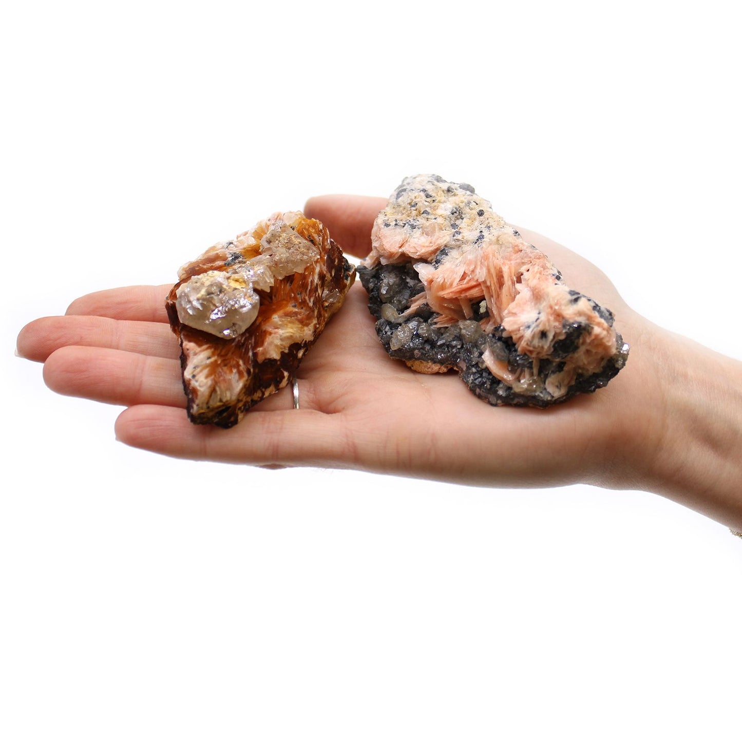 Zwei rohe Barit-Sericit-Mineralien in einer Hand, mit roten und weißen Kristallen.