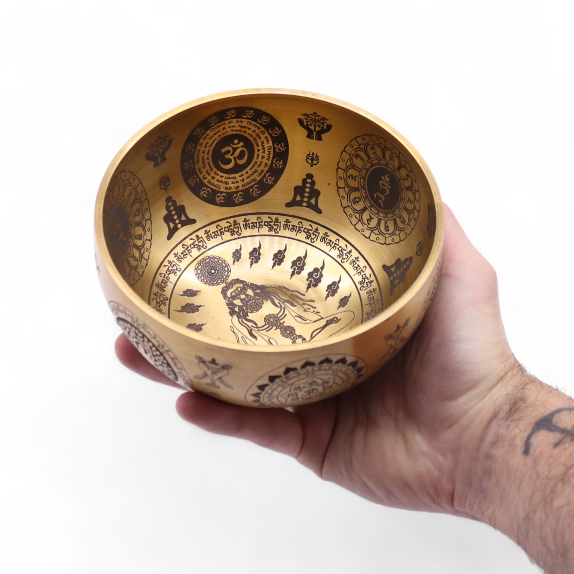Ein handgehaltener, gravierter Messing-Klangschalen-Set mit Yogi-Motiven.