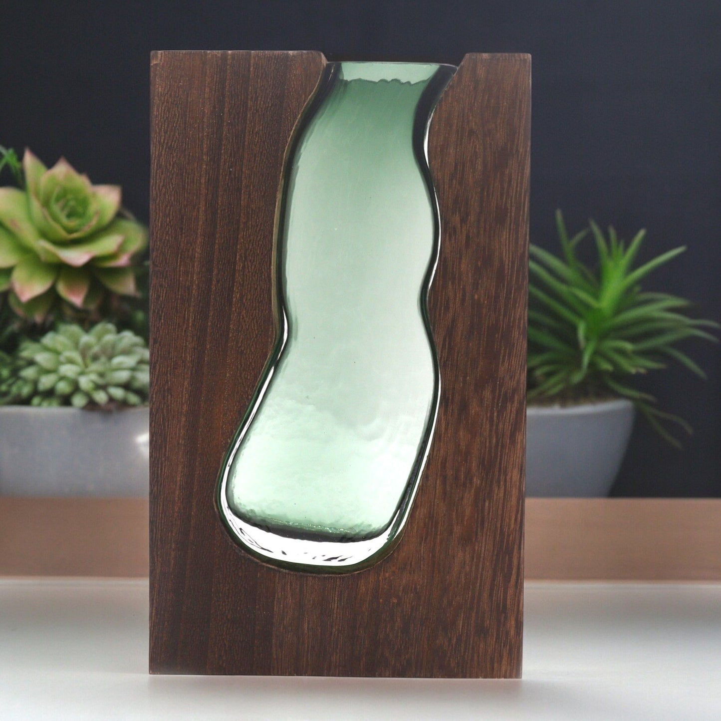 Glass vase with a wavy shape set into a dark tung wood base.