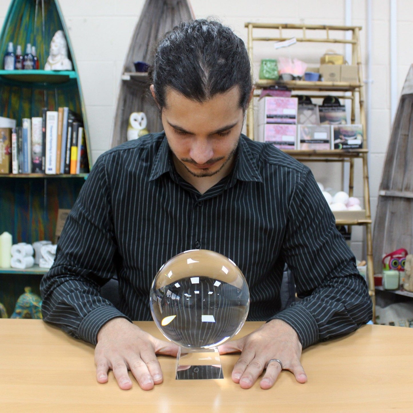 A 150mm crystal ball sits on a stand in front of a man.