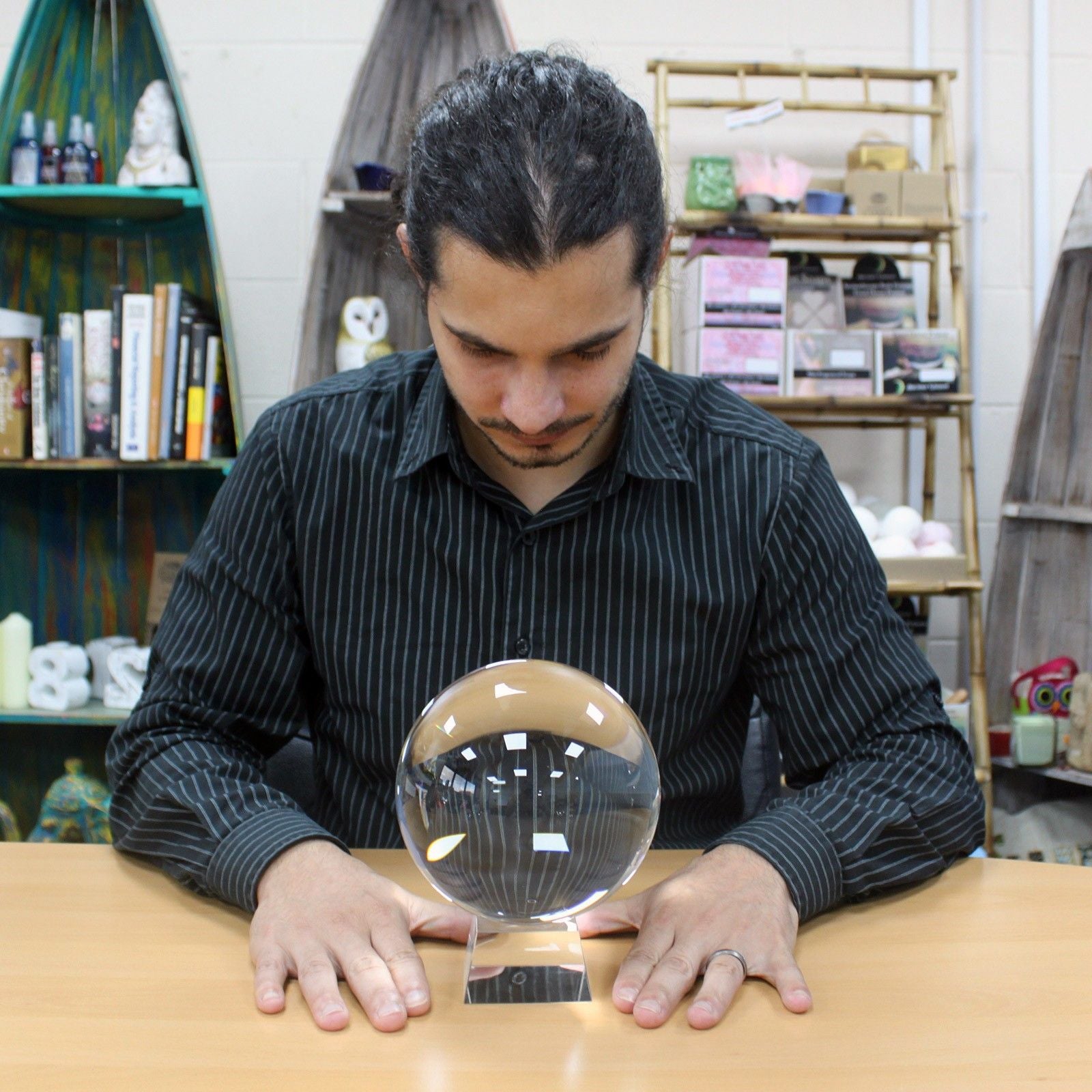 A 150mm crystal ball sits on a stand in front of a man.