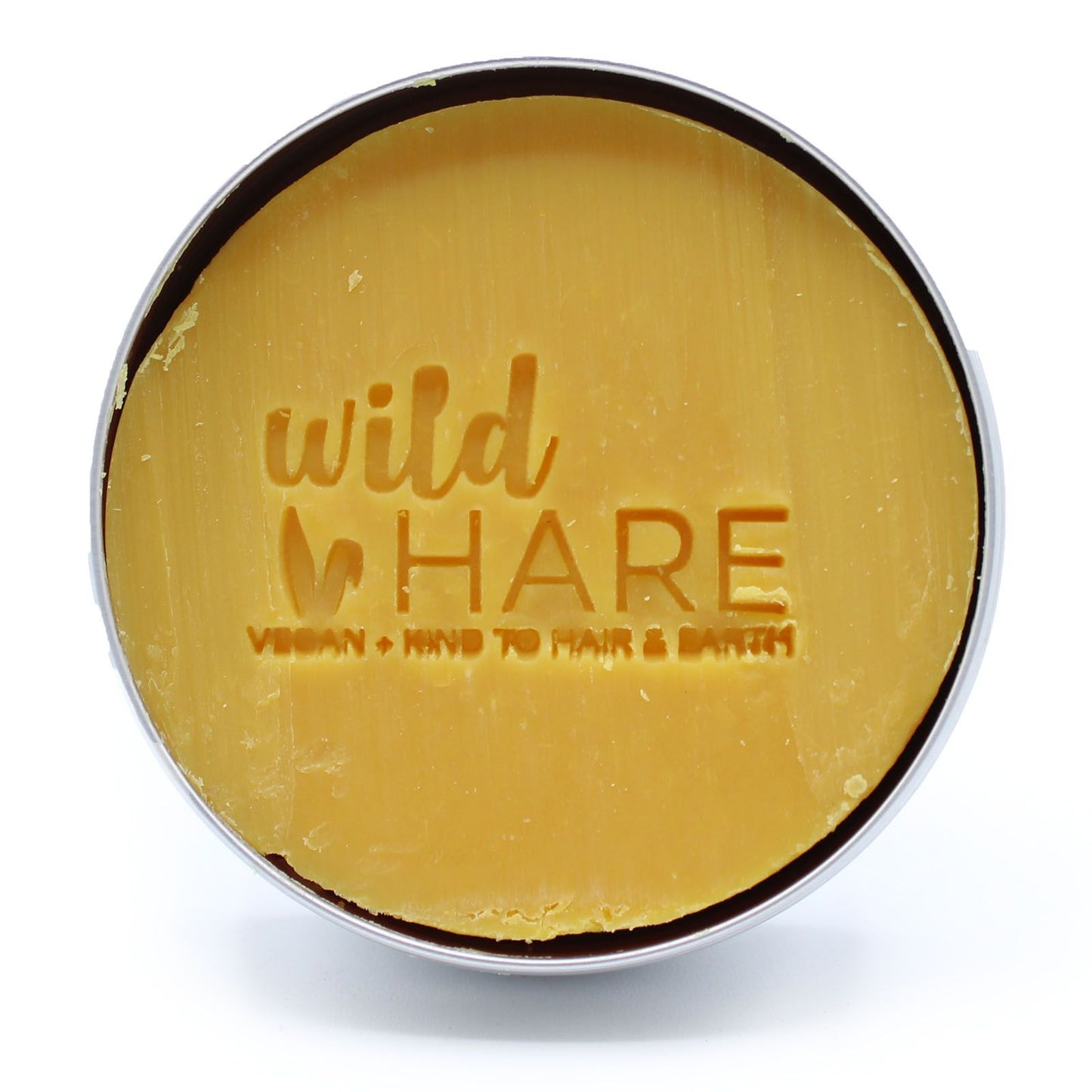 A round, yellow solid shampoo bar with "wild HARE" and "VEGAN KIND TO HAIR & EARTH" embossed on it.