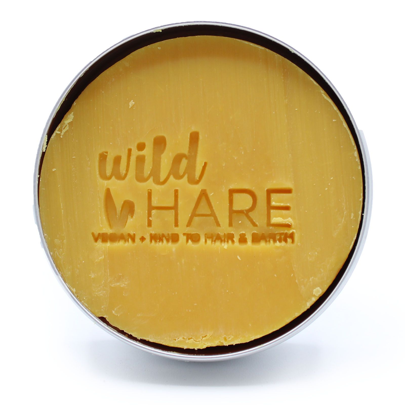 A round, yellow solid shampoo bar with "wild HARE" and "VEGAN KIND TO HAIR & EARTH" embossed on it.