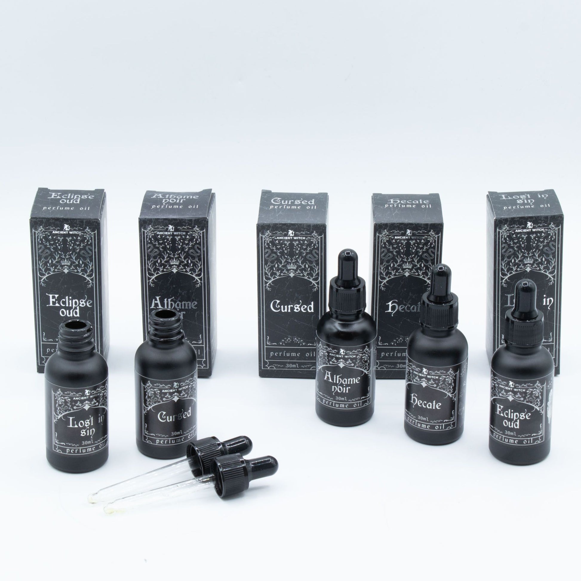 Six bottles of Ancient Witch perfume oil with matching boxes, featuring gothic-style labels.