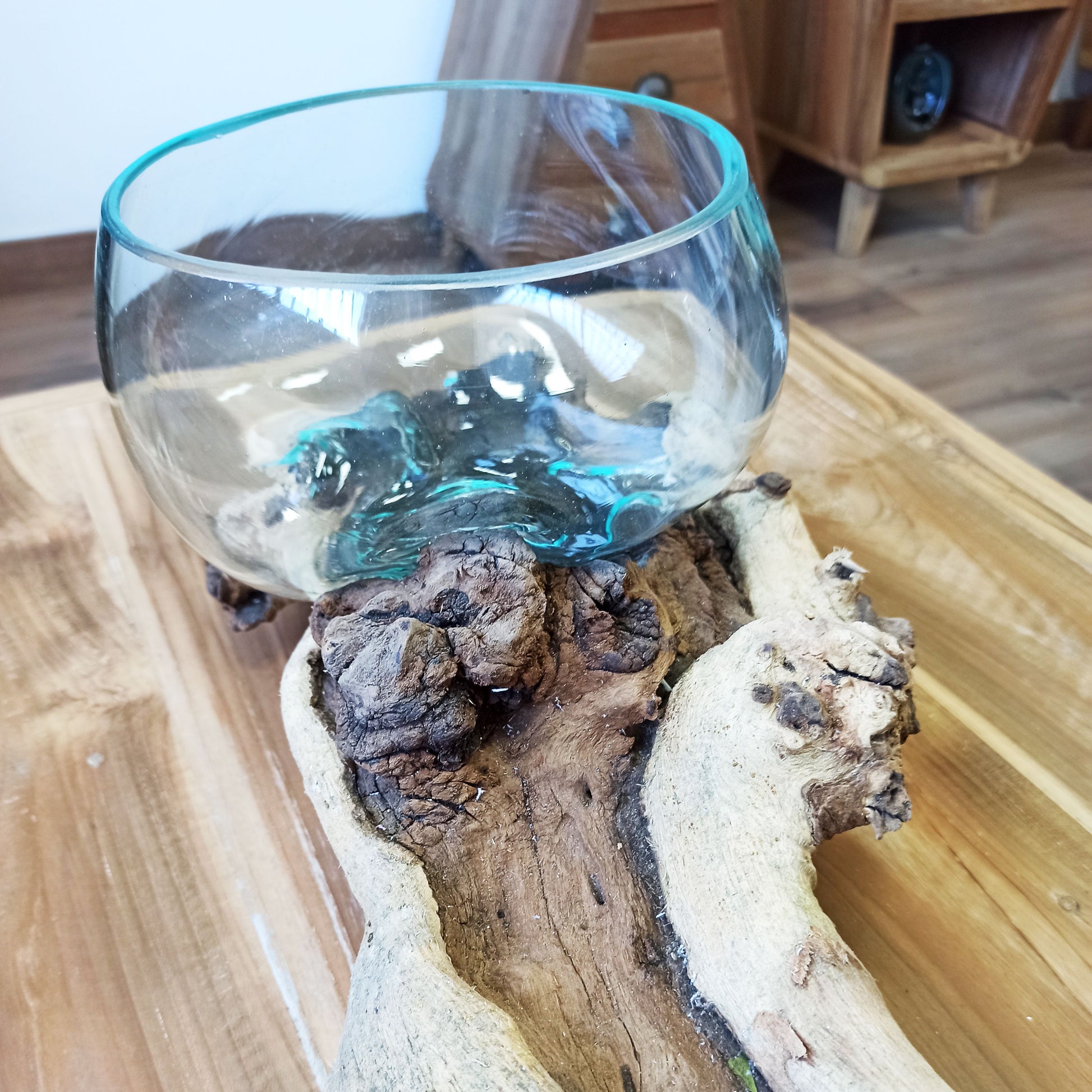 Mundgeblasene Glasschale auf Wurzelholz mit natürlicher Maserung und Glasblasen.