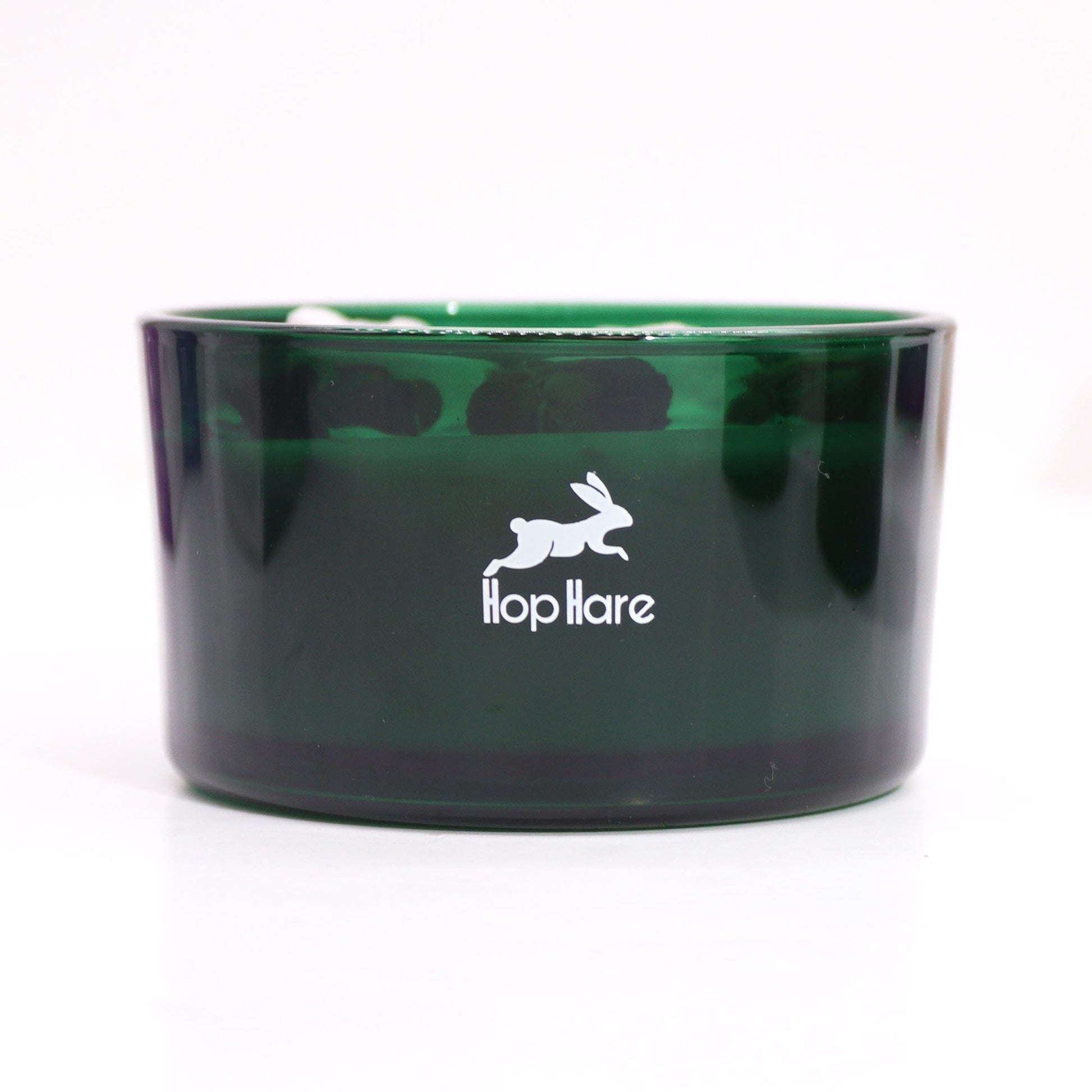 Grüne Glas Kerze mit weißem Hasenlogo und Schriftzug "Hop Hare".