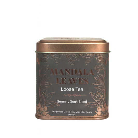 Eine graue Metalldose mit goldener Verzierung, die "Mandala Leaves Loose Tea" und "Serenity Souk Blend" anzeigt.