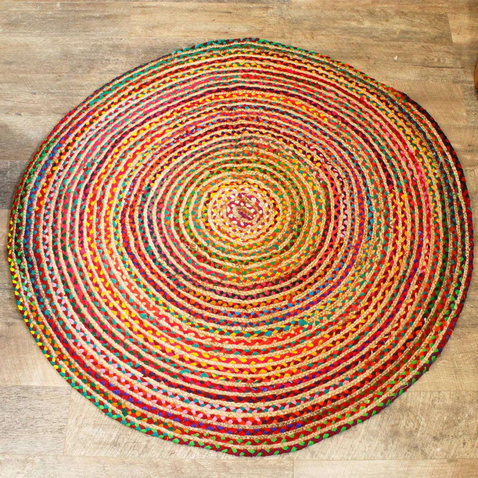 Runder Juteteppich mit recycelter Baumwolle in bunten Spiralen.