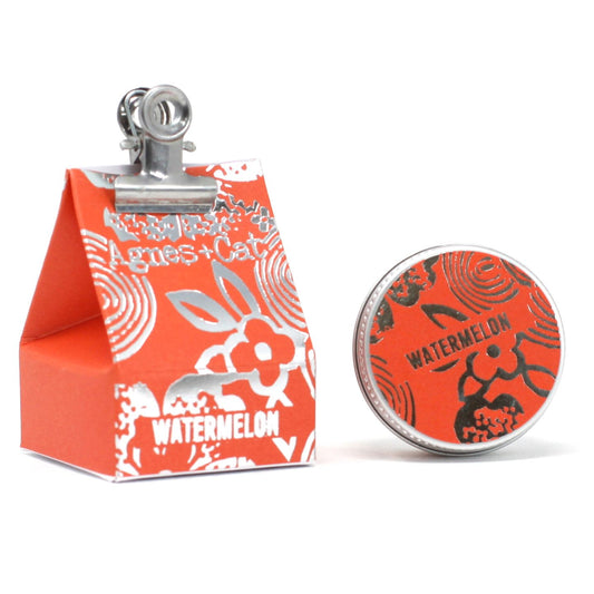 Orange watermelon lip balm in foiled packaging with a small tin.