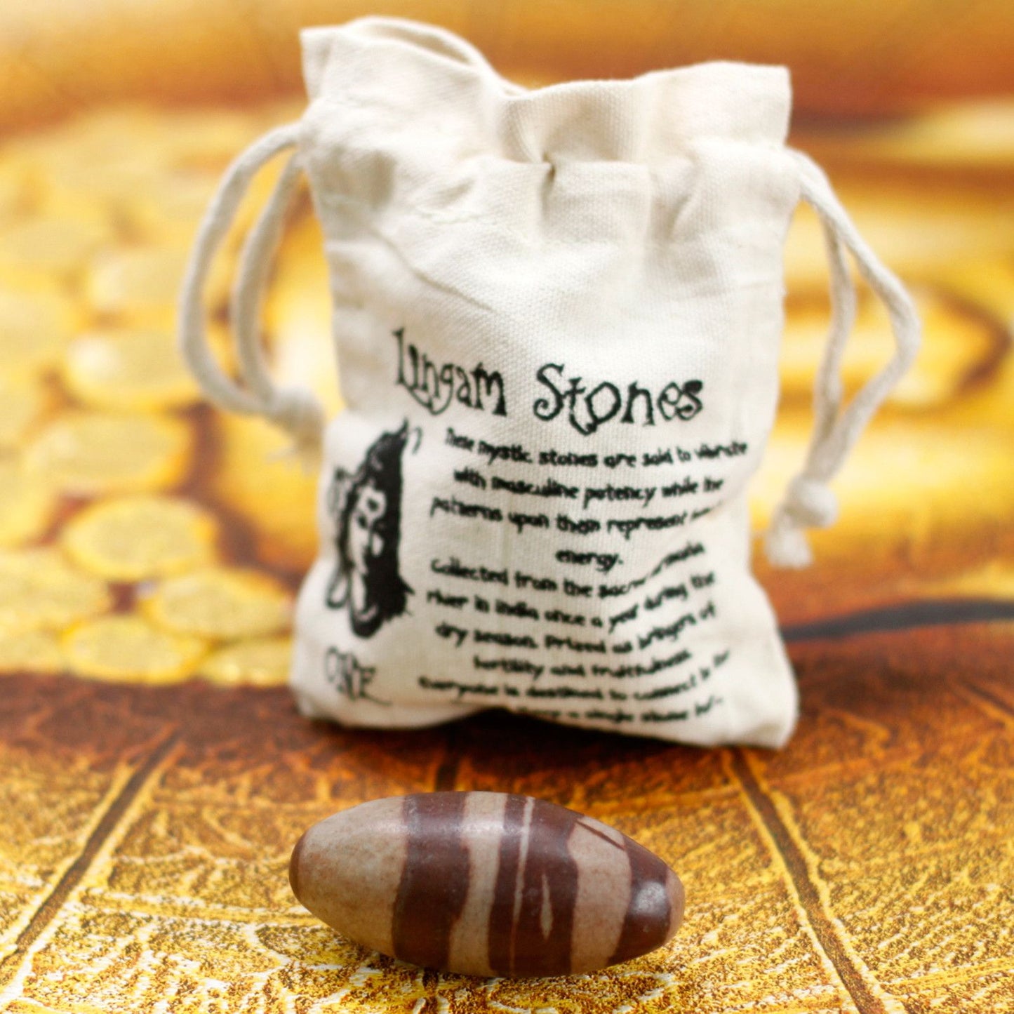 Ein Shiva Lingam Stein mit braunen Streifen liegt vor einem Leinenbeutel.