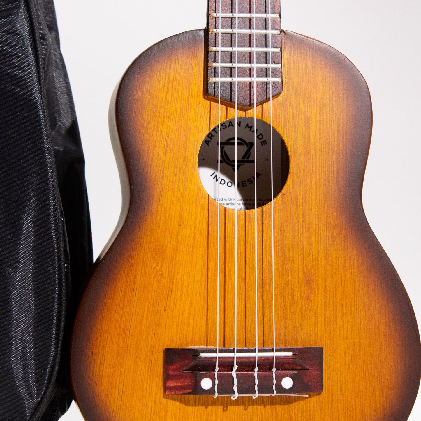 Artisan Made Ukulele with orange sunburst finish and four strings.