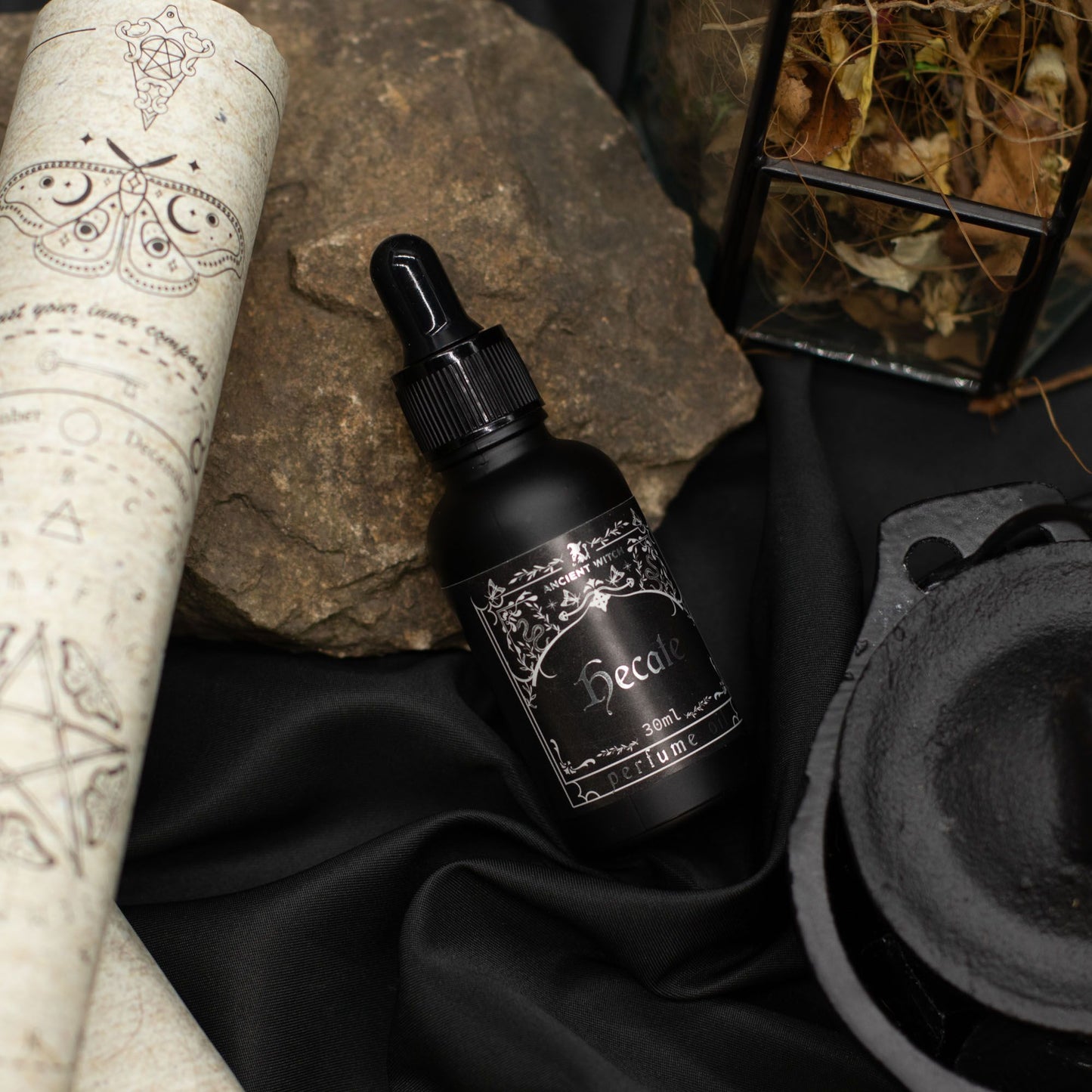 Black bottle of Hecate perfume oil with a scroll and cauldron.