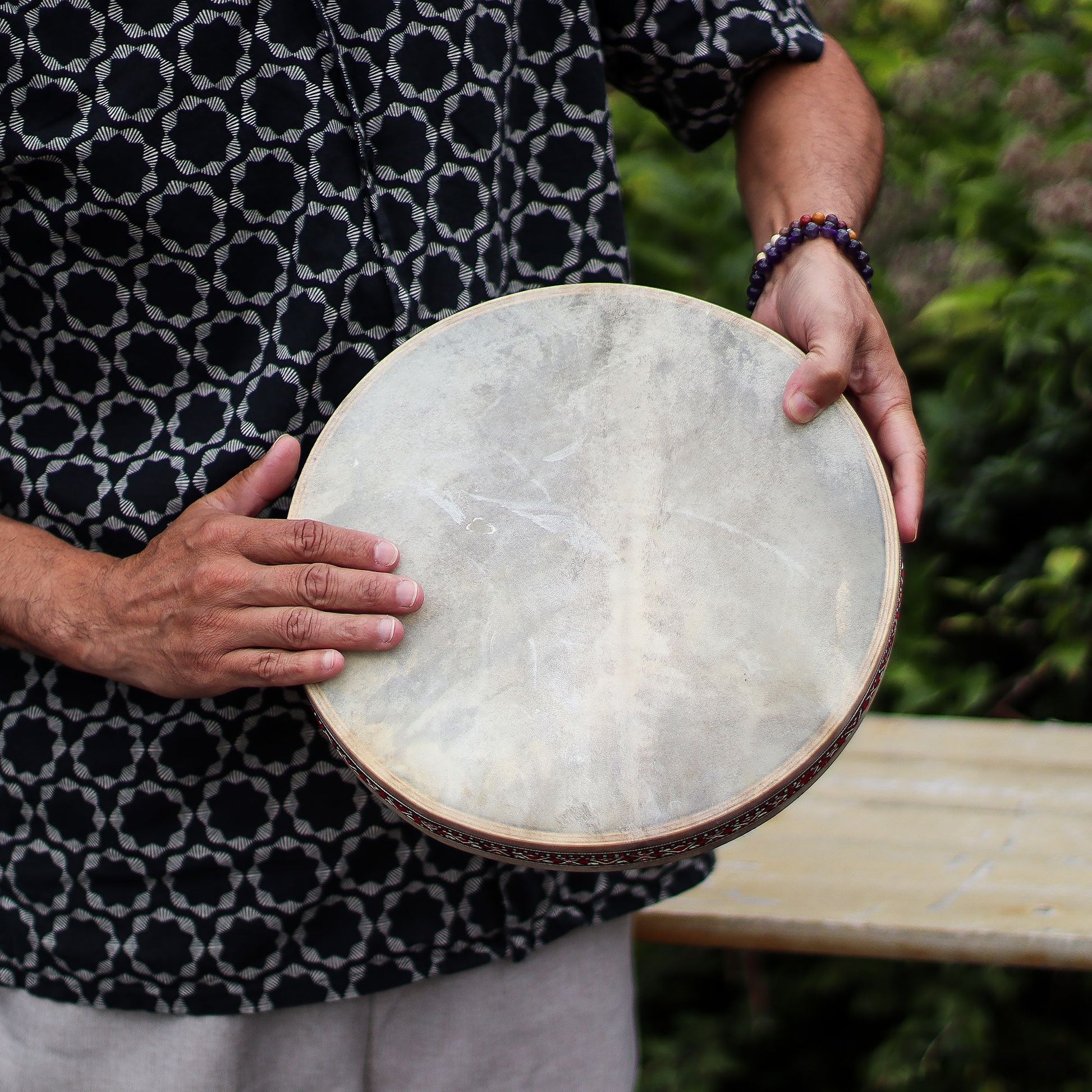 A person holds a 30cm ocean drum with a goatskin head and decorative frame.