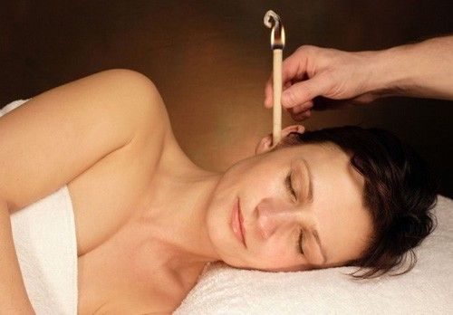 Two lavender-scented ear candles being used in a spa treatment.