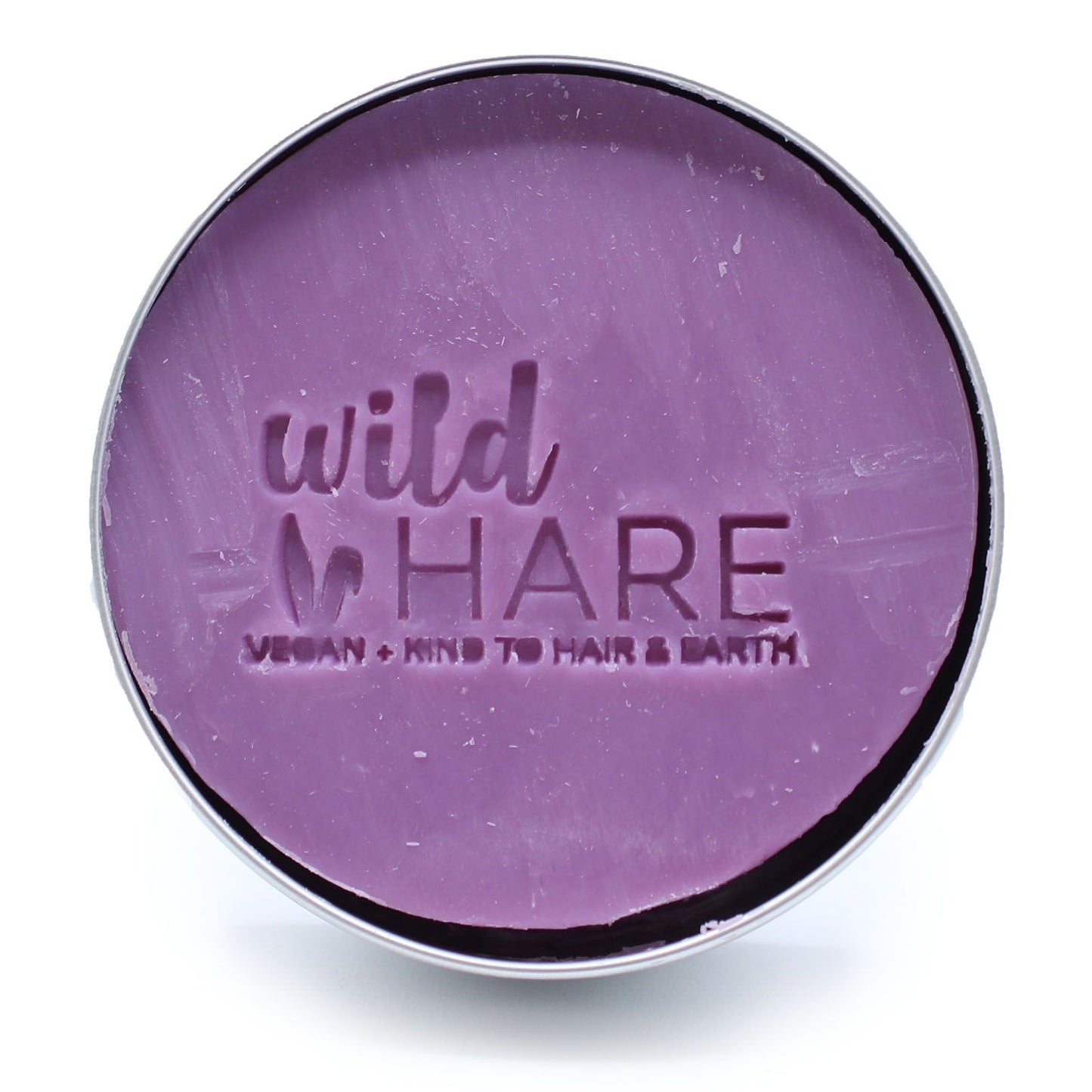 A round, purple solid shampoo bar with "wild HARE" and "VEGAN KIND TO HAIR & EARTH" embossed on it.