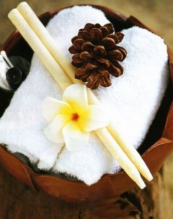 Two lavender scented ear candles with a pine cone and flower on white towels.