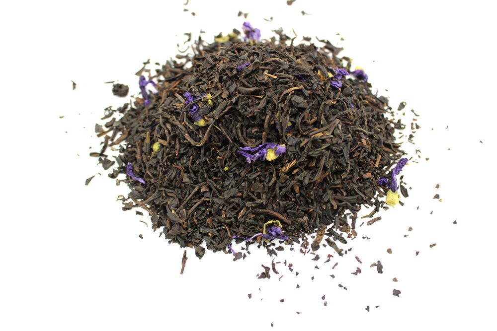 A pile of loose leaf black tea with small purple flower petals.