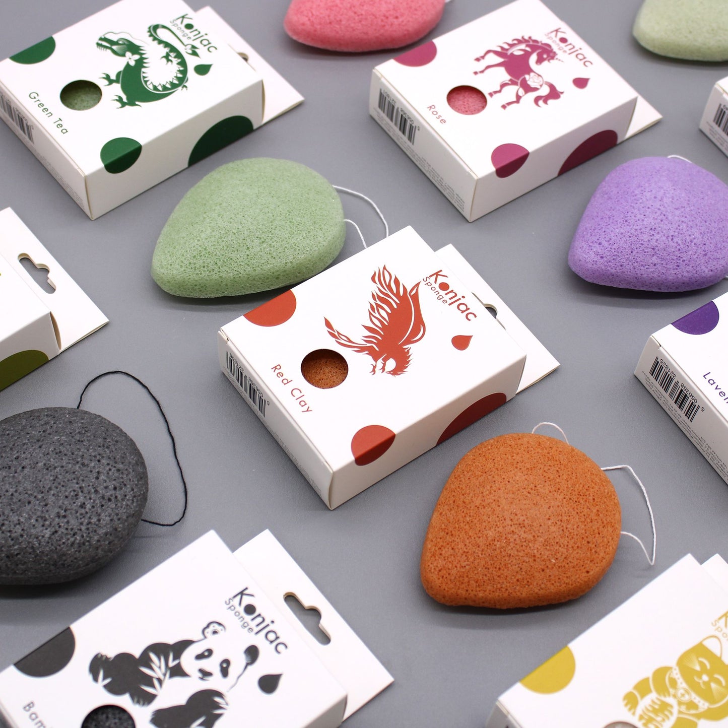 Konjac sponges in various colors and packaging, including green tea, rose, red clay, lavender, bamboo charcoal, and lucky cat.