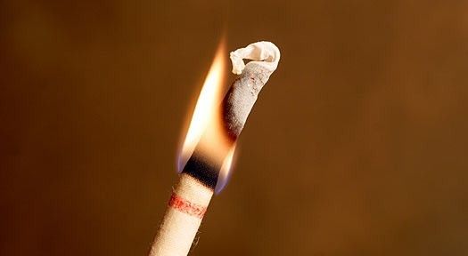 A lit lavender scented ear candle with a brown background.