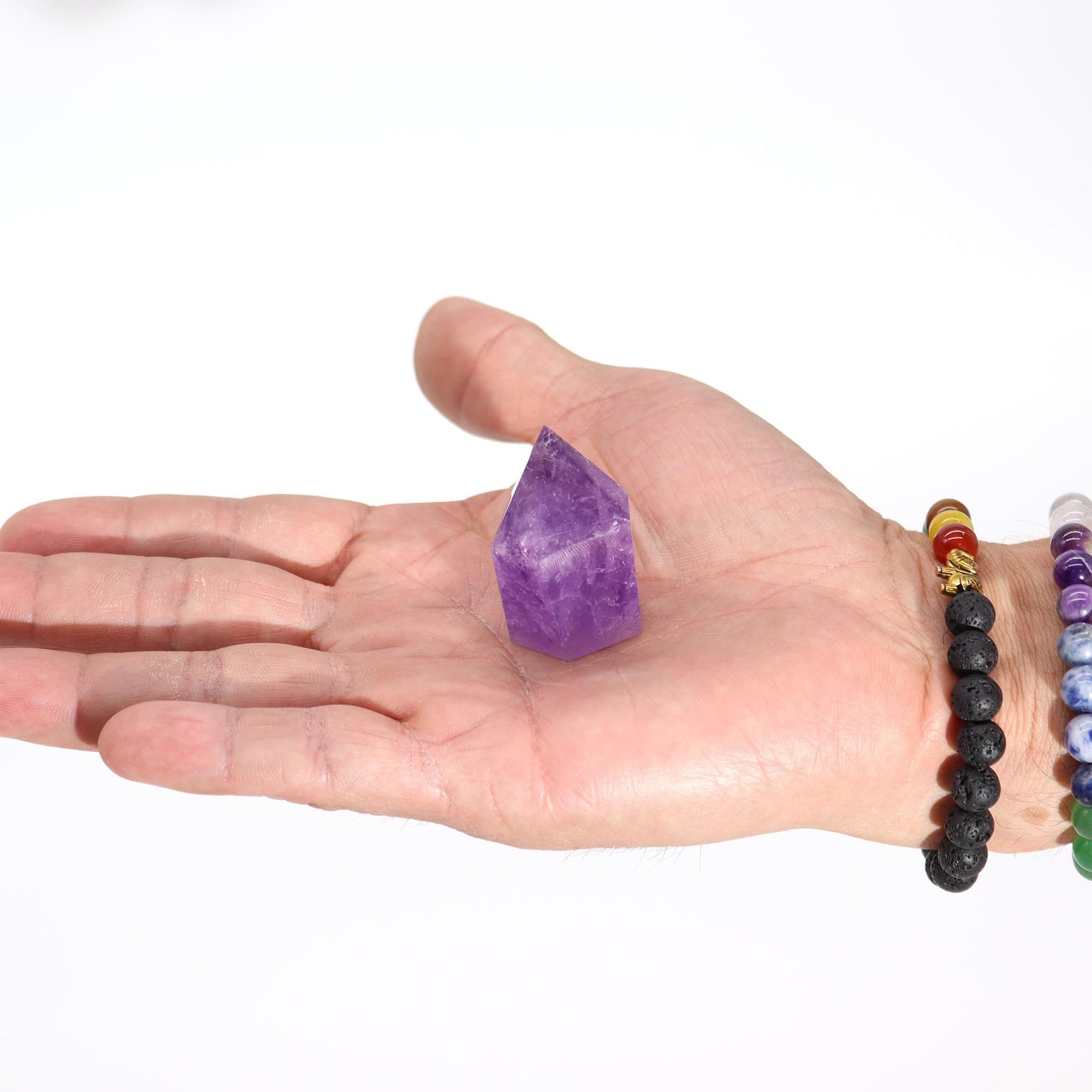 Eine Hand hält eine natürliche, violette Amethyst-Kristallspitze.