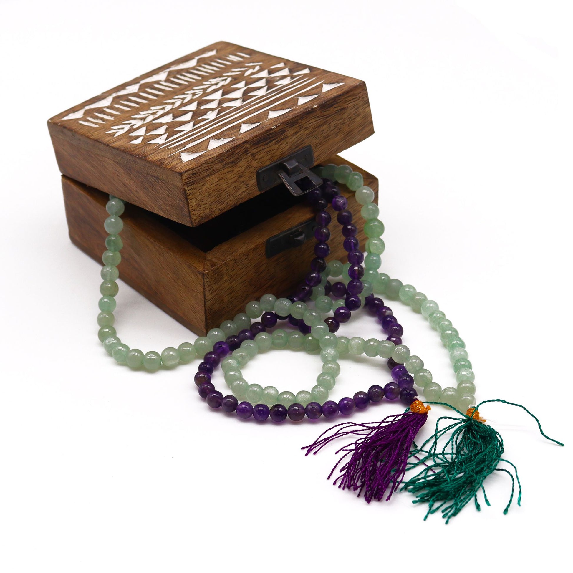 Wooden box with carved lid holding amethyst and green jade mala beads.