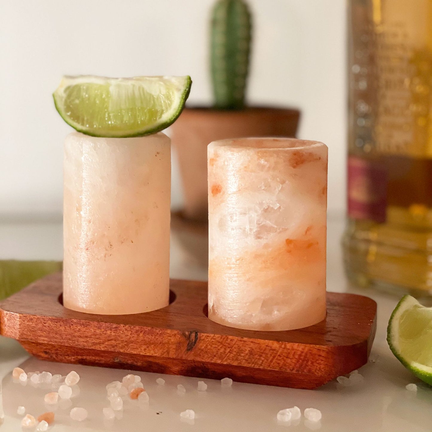 Set aus 2 Shotgläsern aus Himalaya-Salz mit Holzständer und Limettenscheiben.