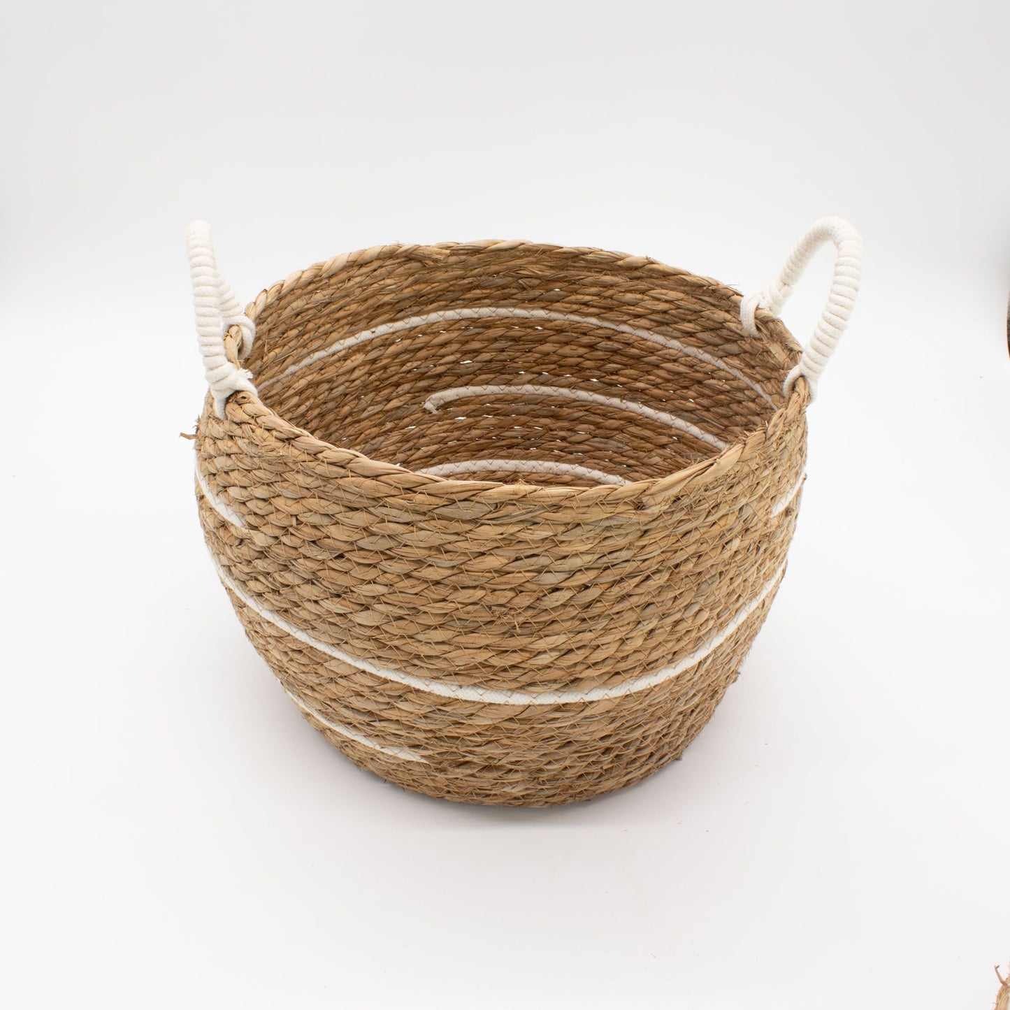 A round, natural seagrass basket with white stripes and rope handles.