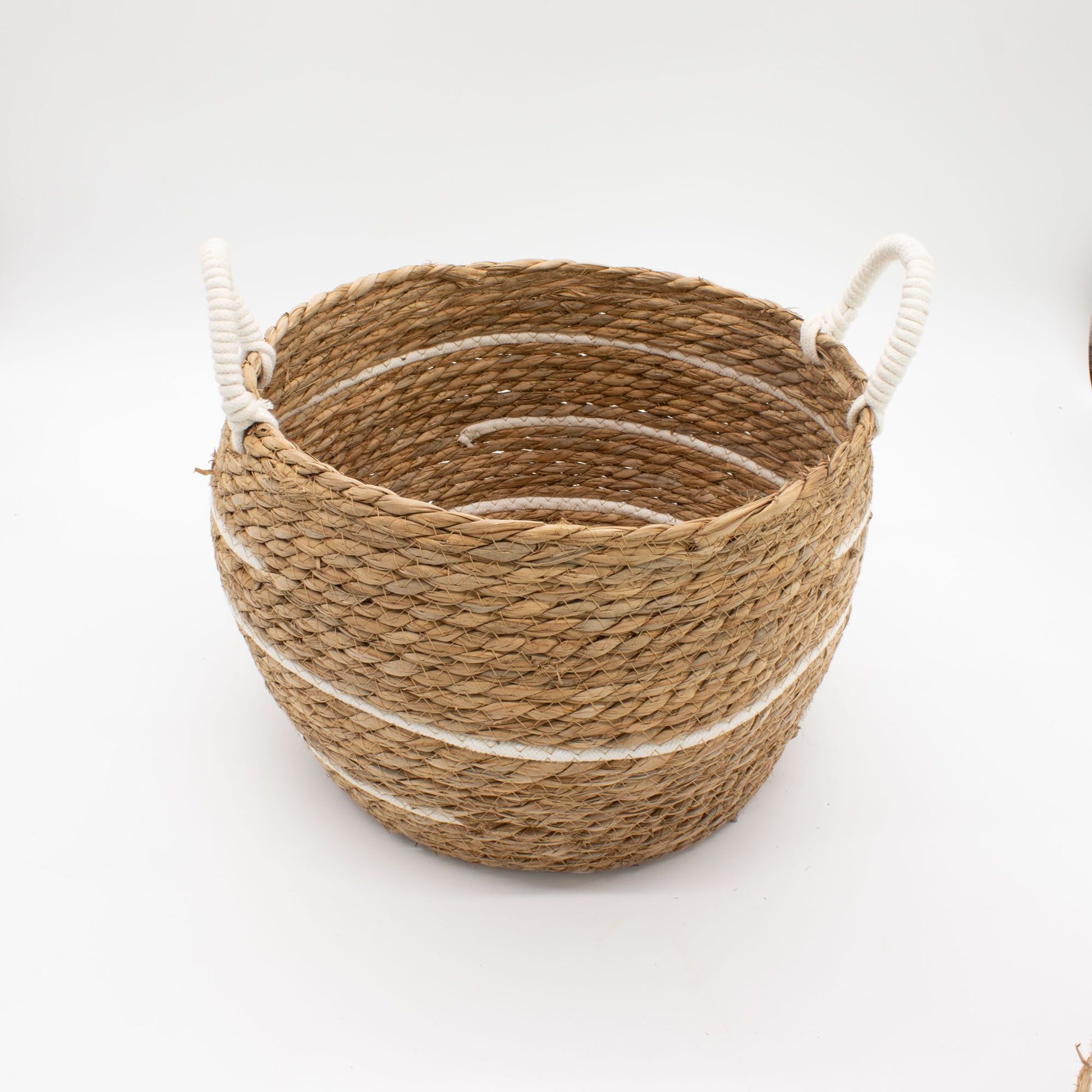 A round, natural seagrass basket with white stripes and rope handles.