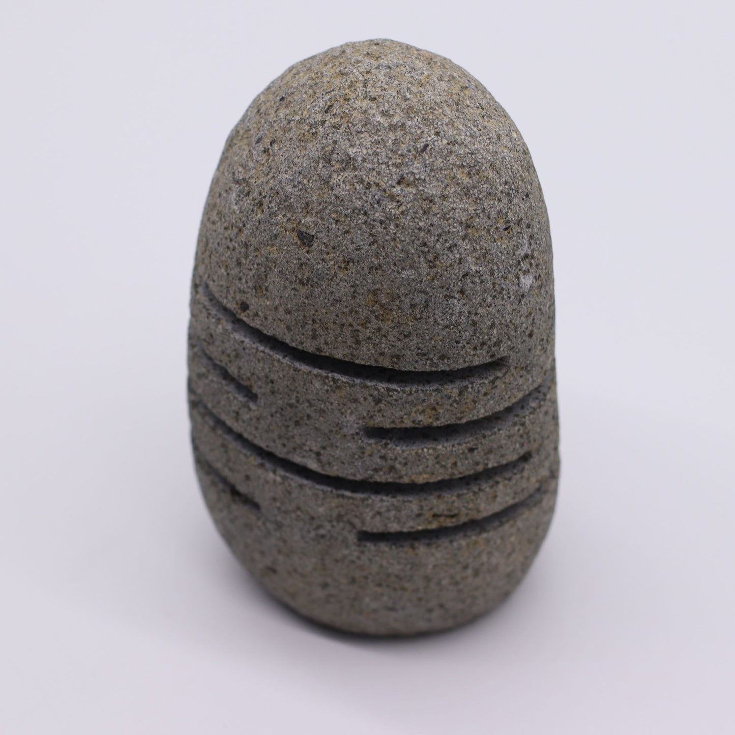 Kerzenhalter aus grauem Flussstein mit horizontalen Rillen.