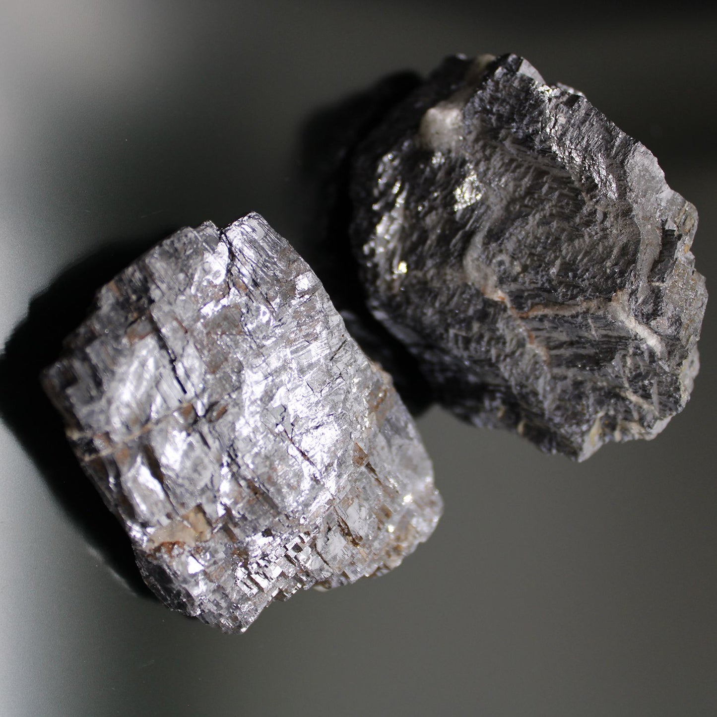 Zwei rohe Galena-Mineralien mit metallischem Glanz und kubischer Kristallstruktur.