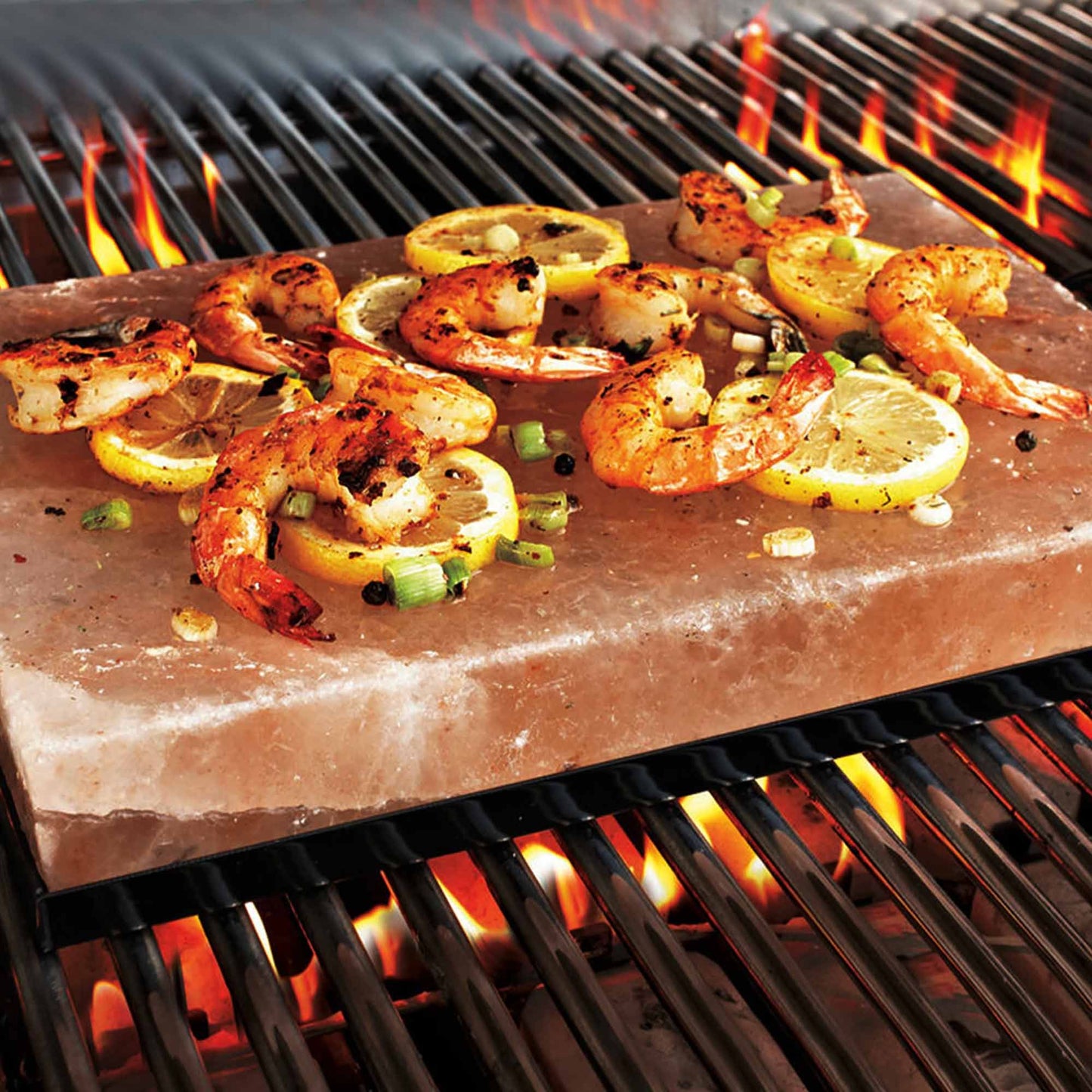 Himalaya-Salz-Platte mit gegrillten Garnelen und Zitronenscheiben auf einem Grill.