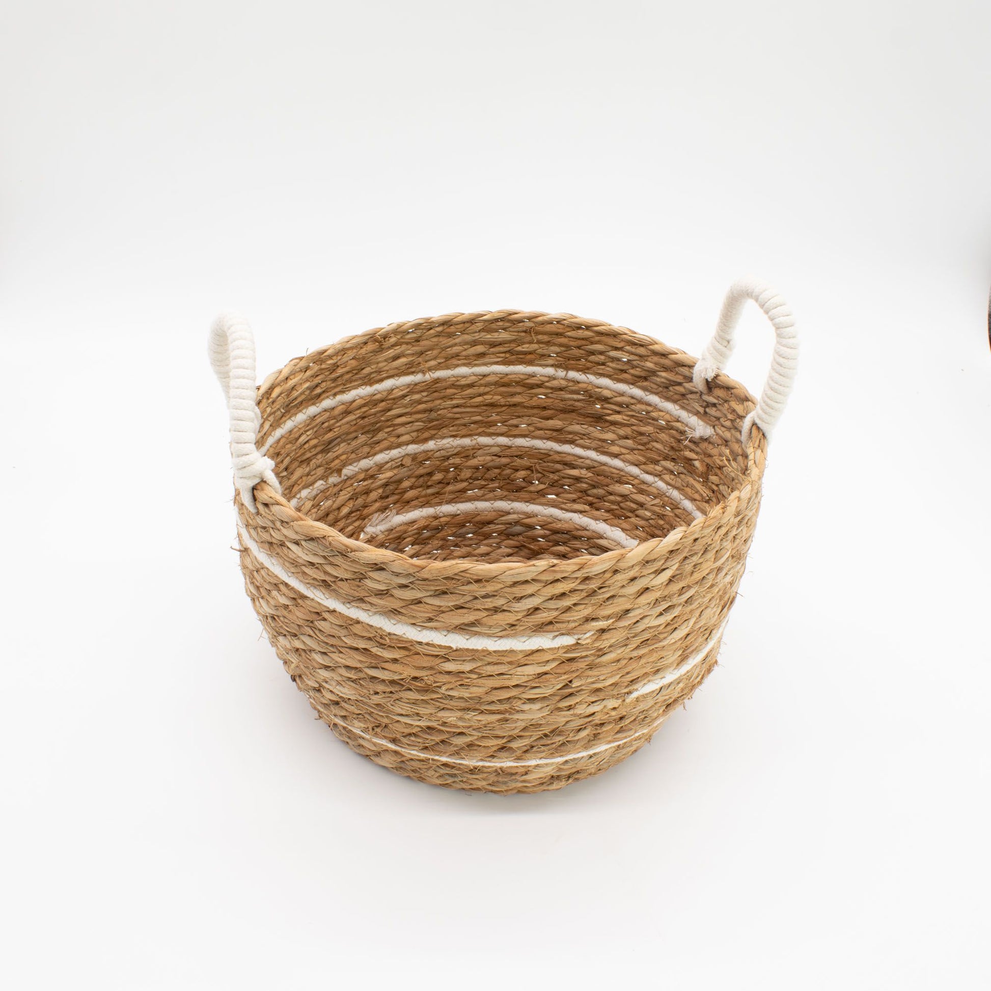 A round, natural seagrass basket with white stripes and rope handles.
