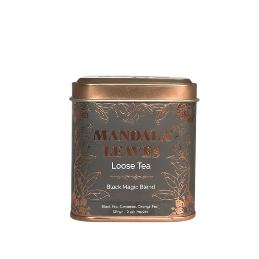 Eine graue Teedose mit goldenen Blättern und der Aufschrift "Mandala Leaves Loose Tea Black Magic Blend".