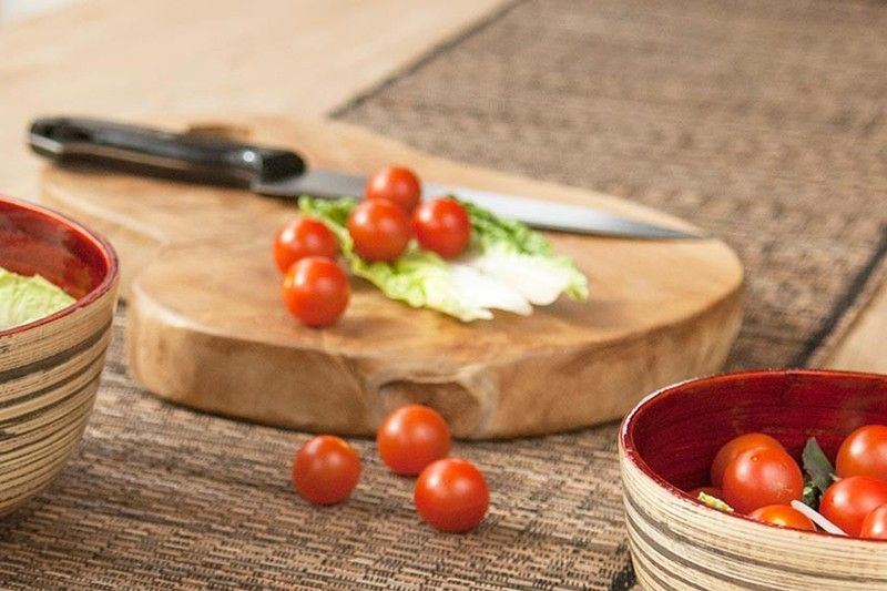 Handgefertigtes Teakholzschnittbrett mit Tomaten und Salat.