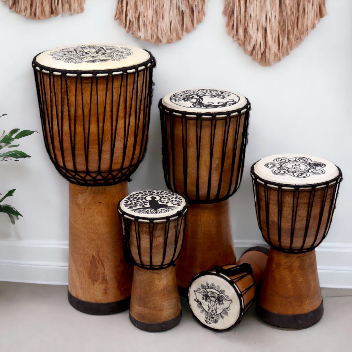 Five wooden djembe drums of varying sizes with decorative tops.