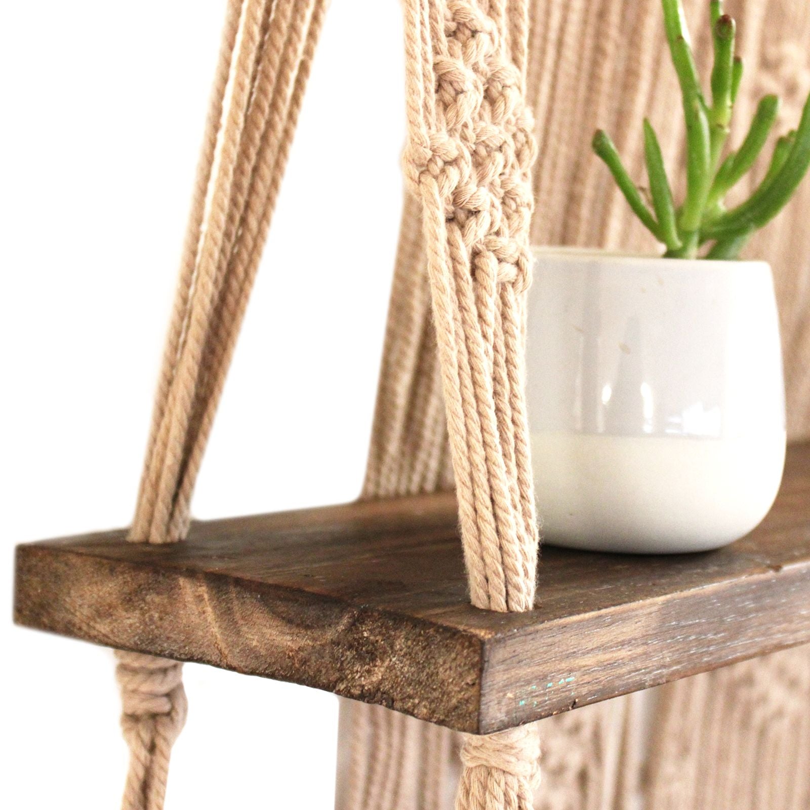 Dekoratives Makrame-Hängeregal aus Holz mit Baumwollseilen im Boho-Stil.