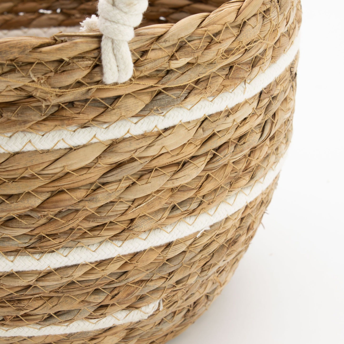 A natural seagrass basket with white stripes and rope handles.